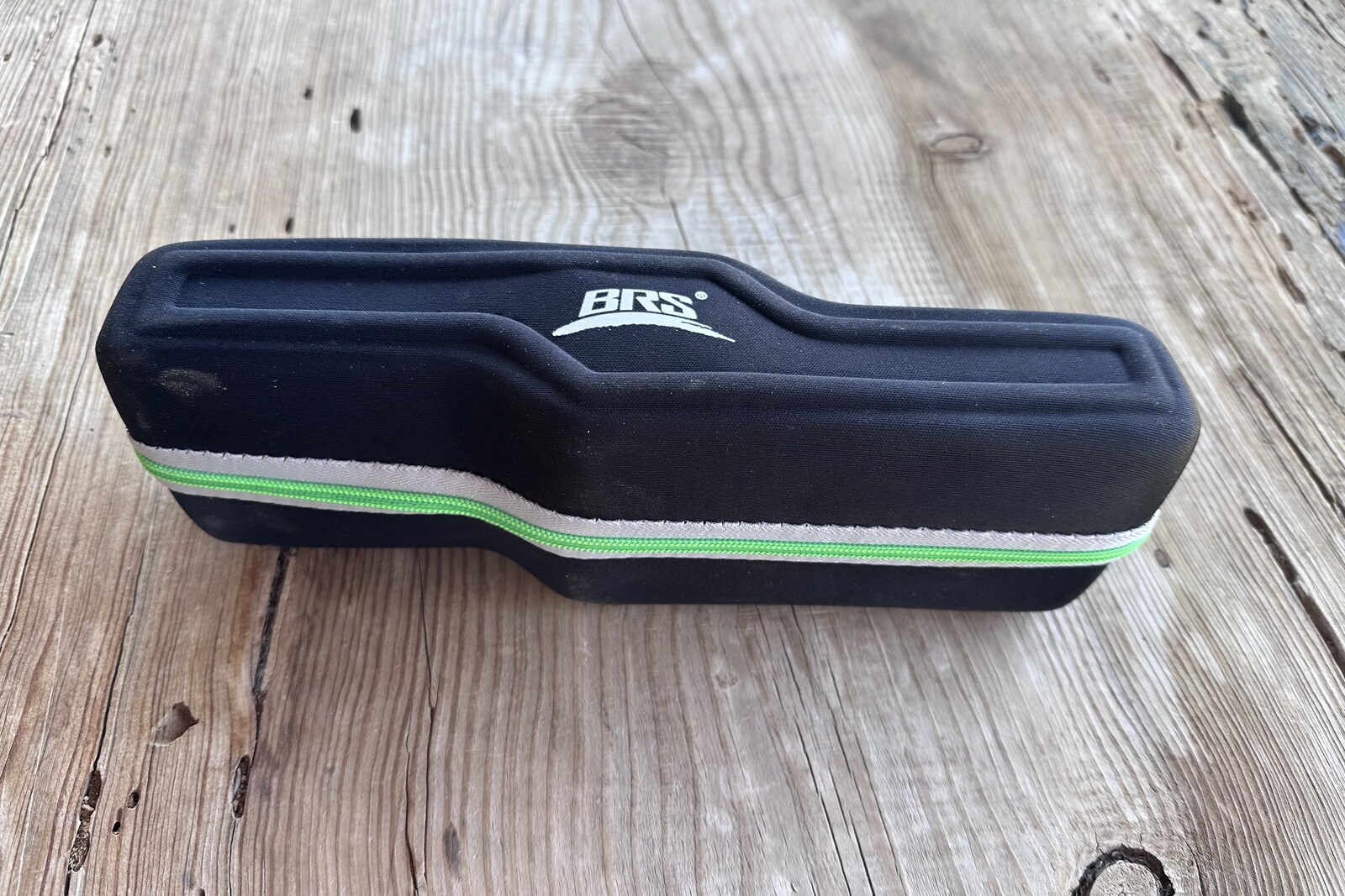 A small, zippered black pouch sits on a wooden table.