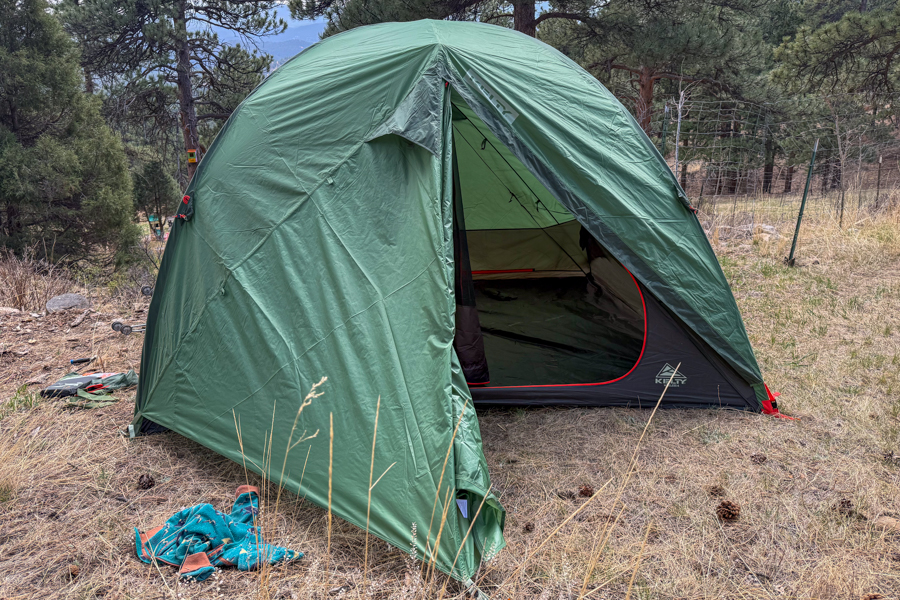 Front view of the Kelty Wireless 6 tent pitched at camp with the vestibule open and the front door visible inside.