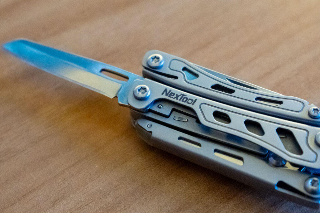 A multi tool on a desk with the knife extended