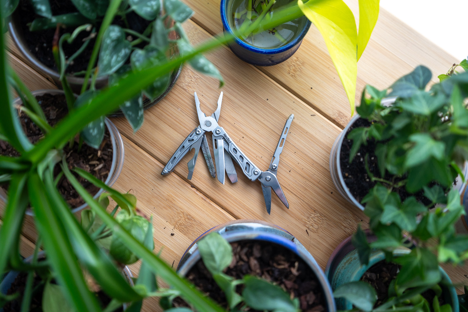 A multi tool sits on a table surrounded by plants