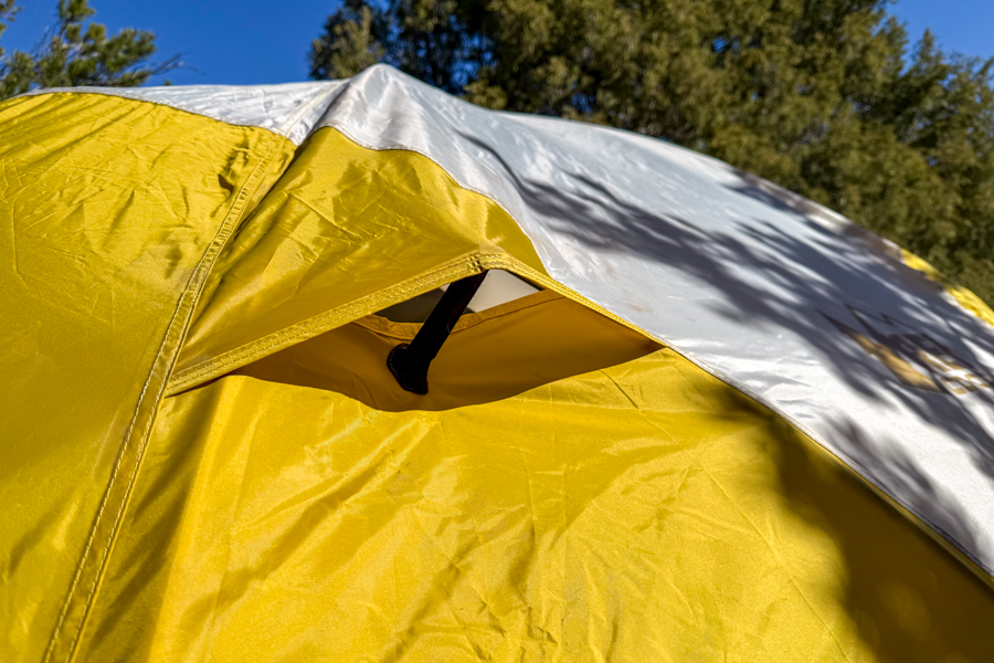 Close-up of one of the REI Base Camp 6 tent's roof vents propped open beneath the rainfly.