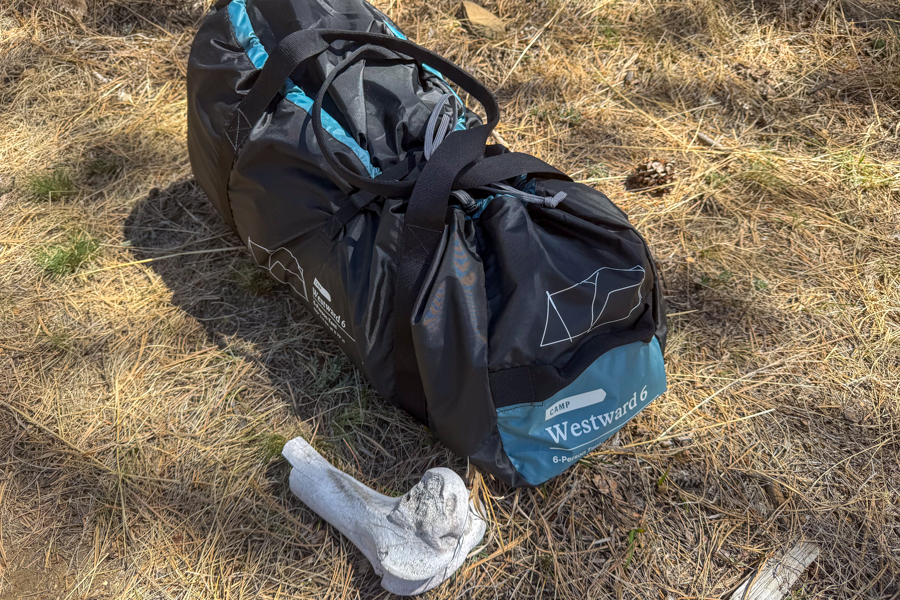 The REI Westward 6 tent's carry bag resting on dry grass at camp.