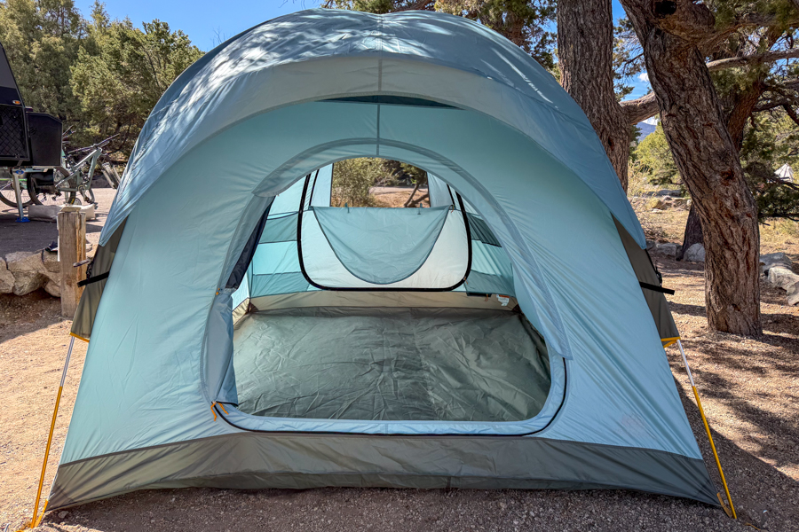 The REI Westward 6 tent pitched with the rainfly on and the front door open, showing the tall entry and broad interior.