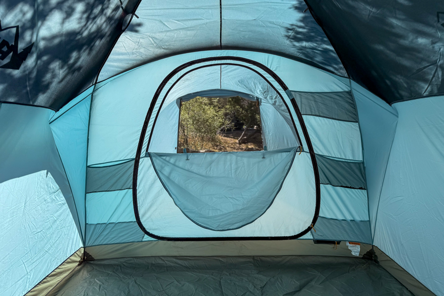 Interior view of the REI Westward 6 tent looking toward the rear door and window, showing the open layout and mesh side panels.