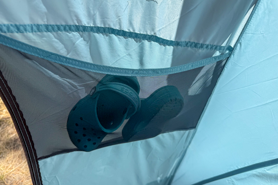 Close-up image of the mesh wall pocket inside the REI Westward 6 tent holding a pair of children’s Crocs.