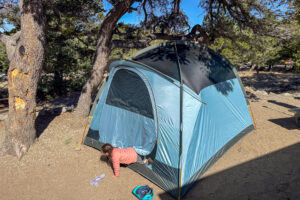The REI Westward 6 tent pitched at camp with the rainfly and front vestibule fully set up.