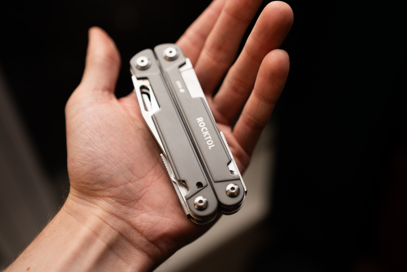 A hand holds a multitool in its palm