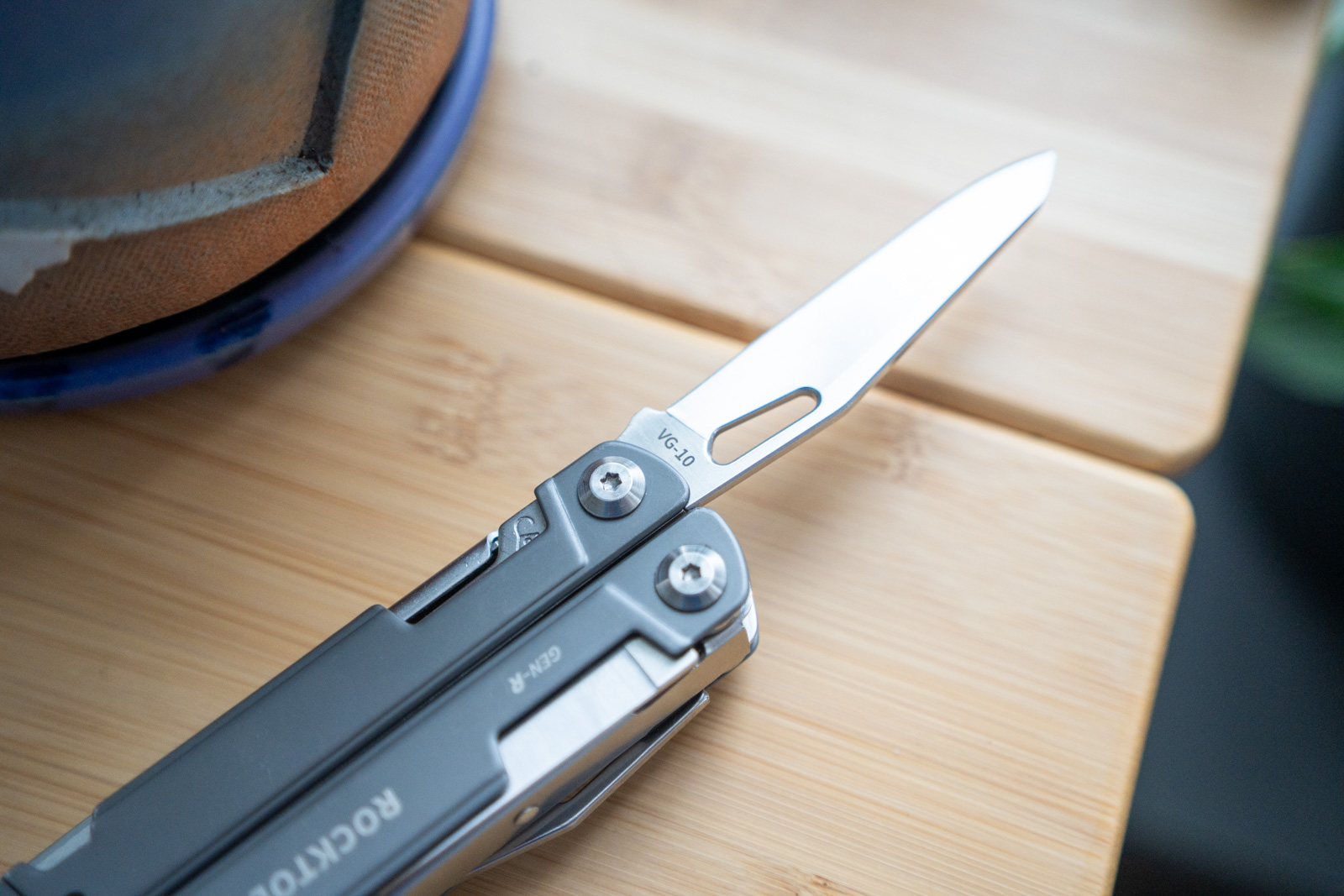 A multi tool sits on a table with its blade extended