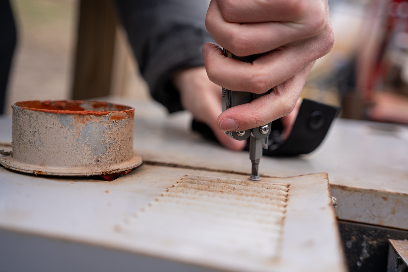 A hand uses a screwdriver on a multi tool to tighten a screw