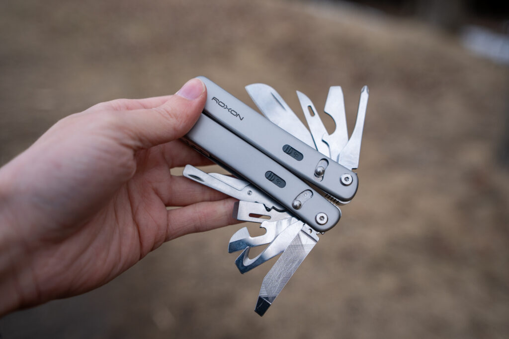 A hand holds a multi tool with all of its implements spread