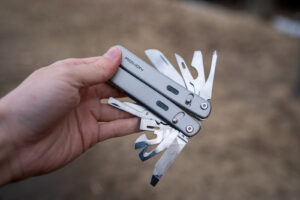 A hand holds a multi tool with all of its implements spread