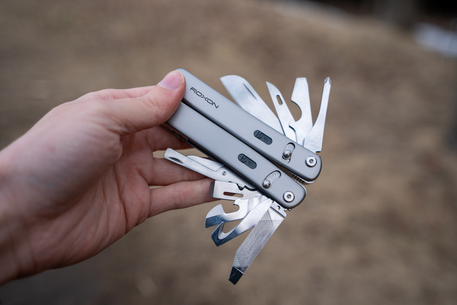 A hand holds a multi tool with all of its implements spread