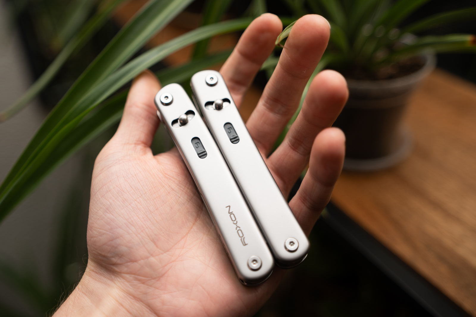 A hand holds a multitool in the palm