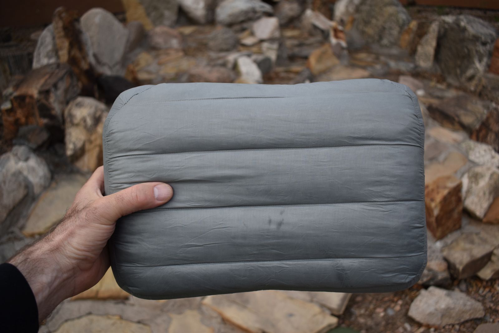 Our tester holds the Aeros Down Pillow in front of a rock feature to show its down top.