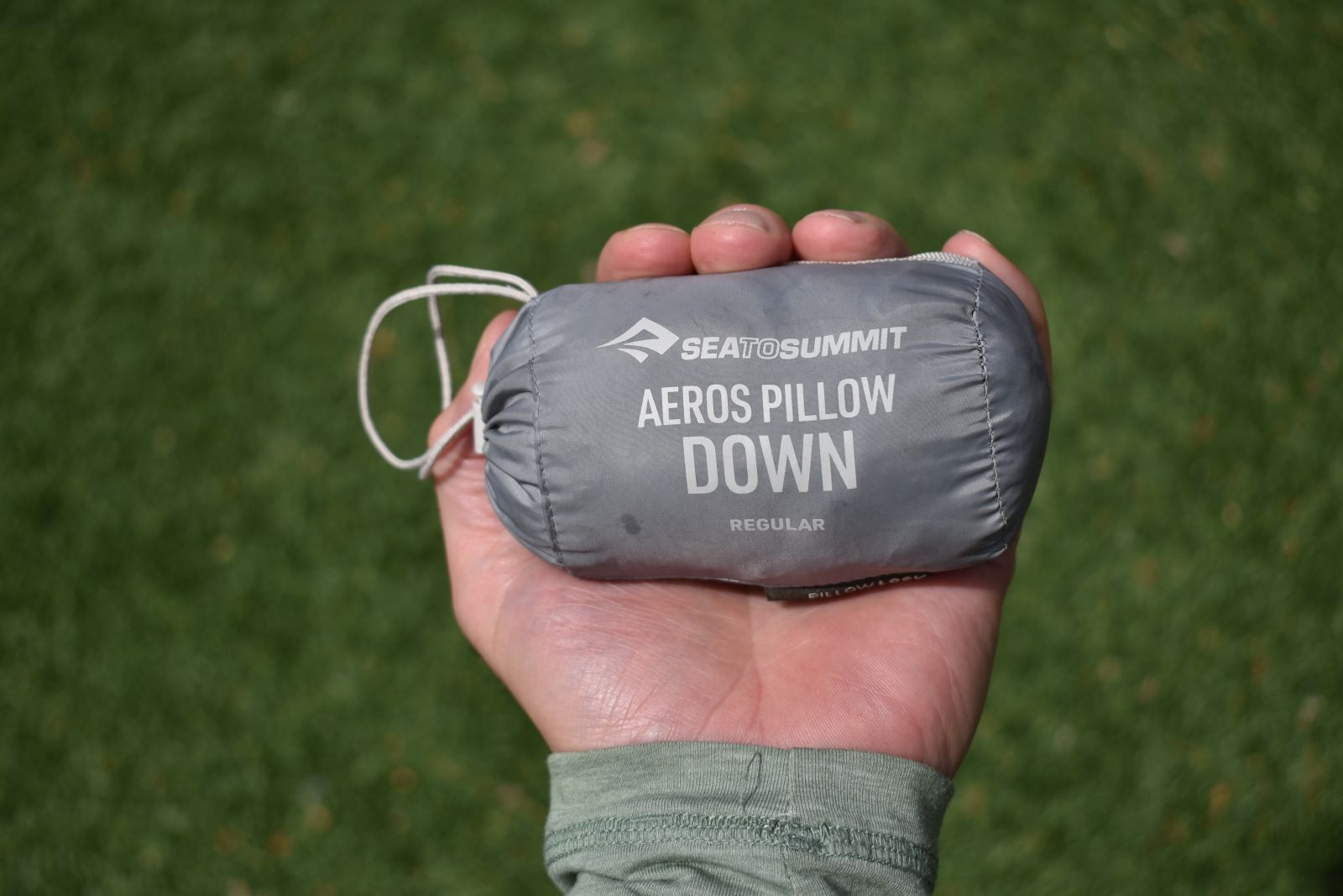 A person holds out the Aeros Down's stuff sack in the palm of his hand, showing off its extremely small packed size.