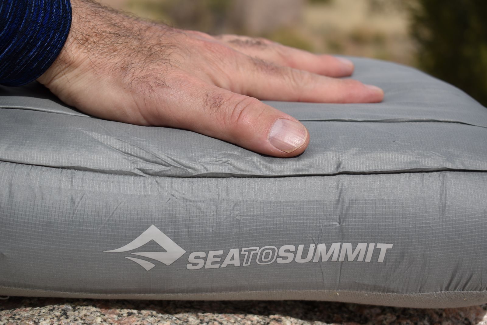 Close up of the Aeros Down Pillow with someone's hand on top pushing down on the down pillow top.