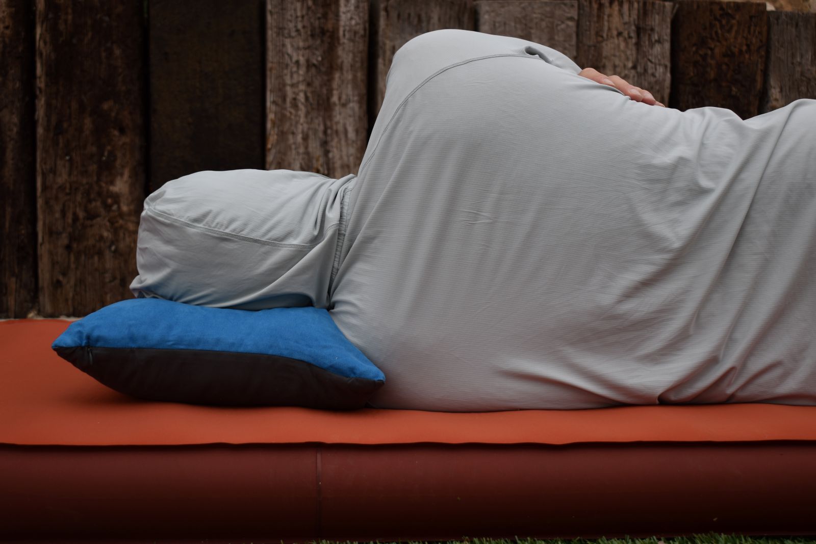 Our tester rests on a blue Wise Owl camping pillow while lying on his side.