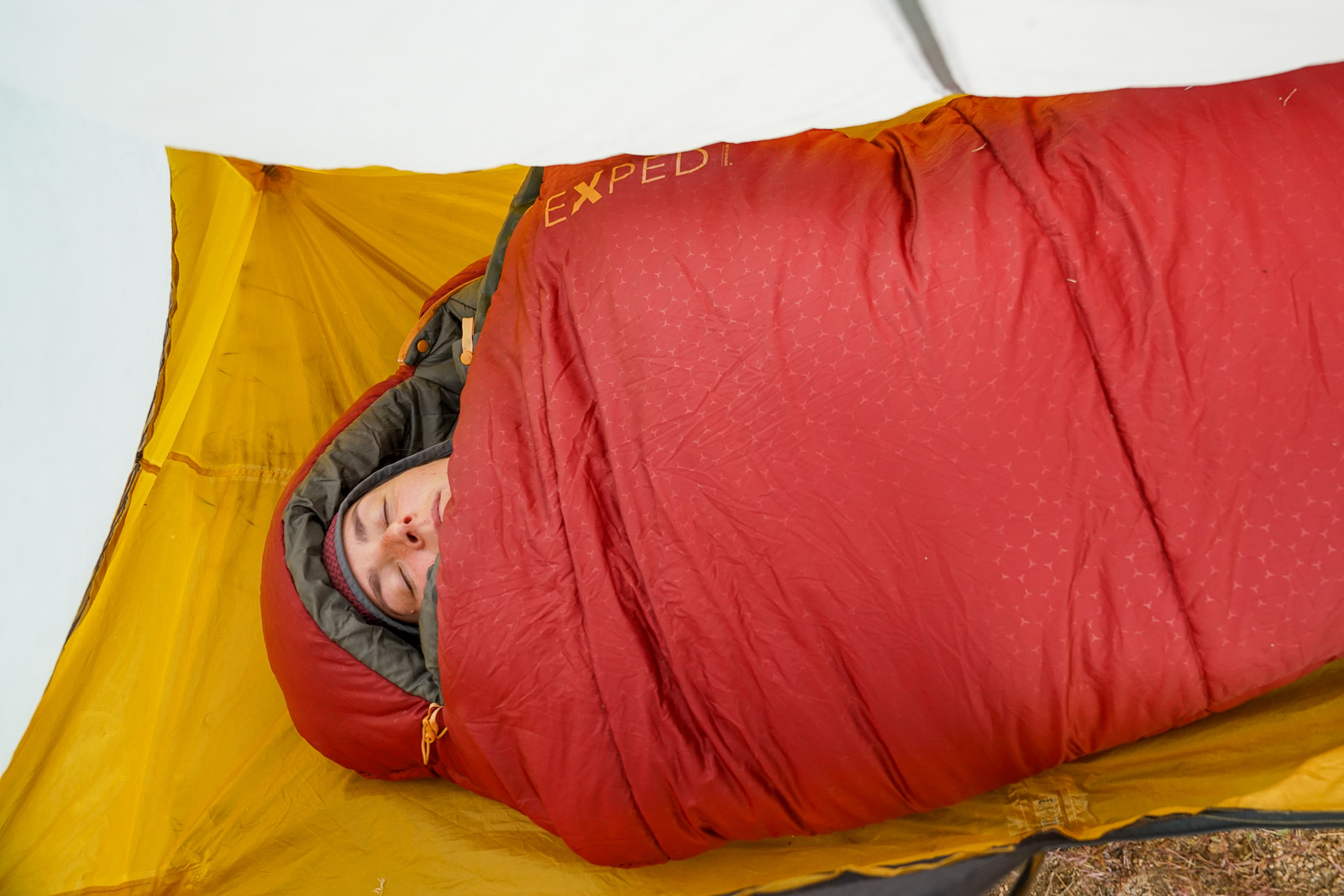 A sleeping person lays in a mummy sleeping bag.