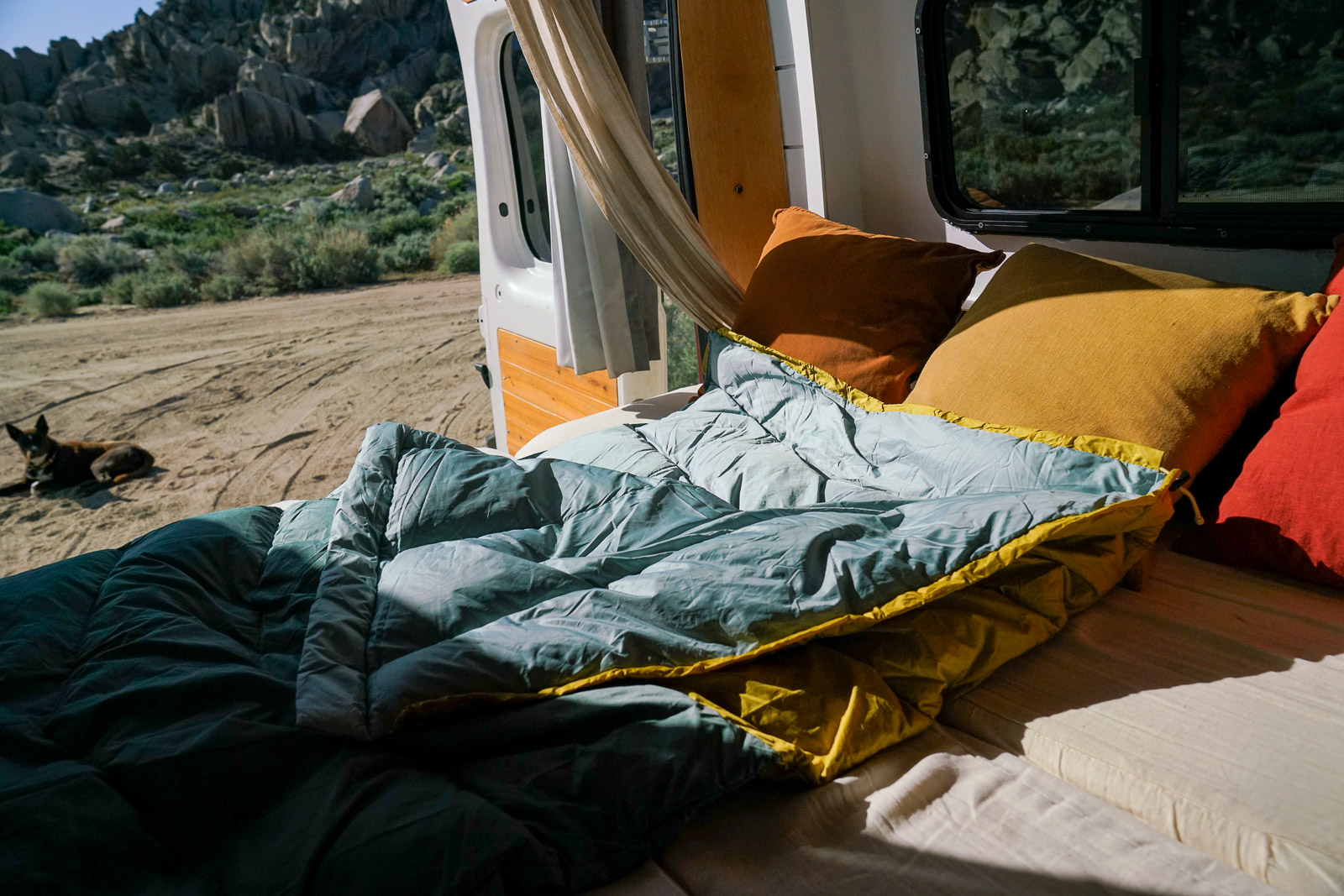 A close up of a sleeping bag laying on the bed of a camper van.