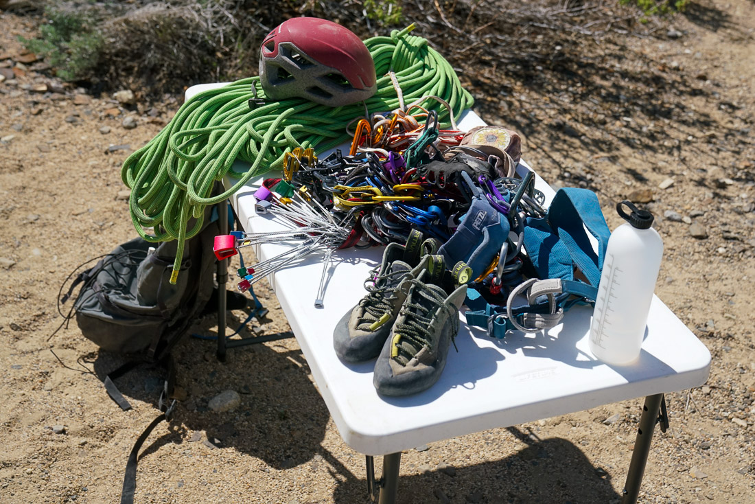 A close up of a variety of climbing gear filling the surface of a folding table.