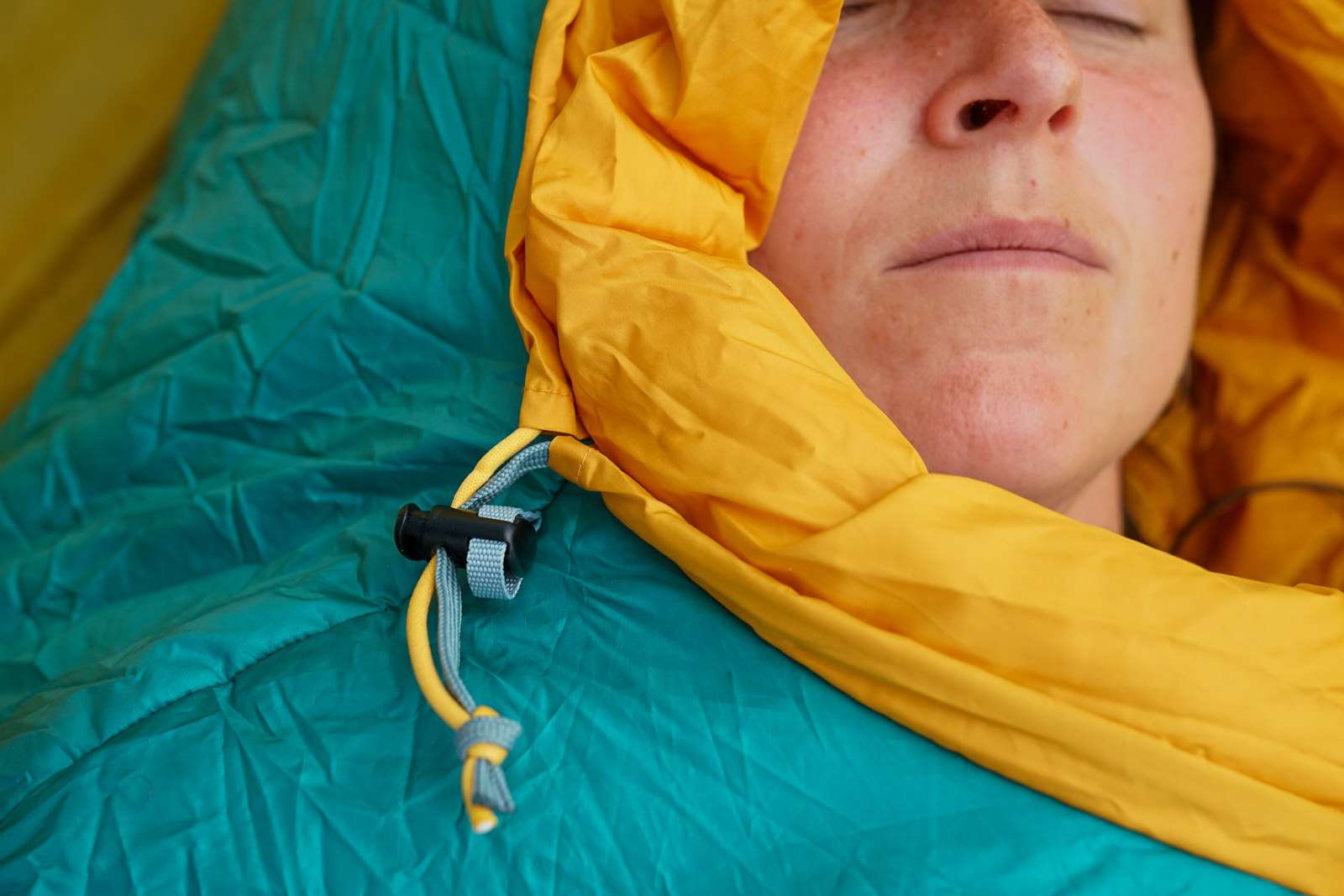 A close up of a plastic toggle and cord of a sleeping bag hood.