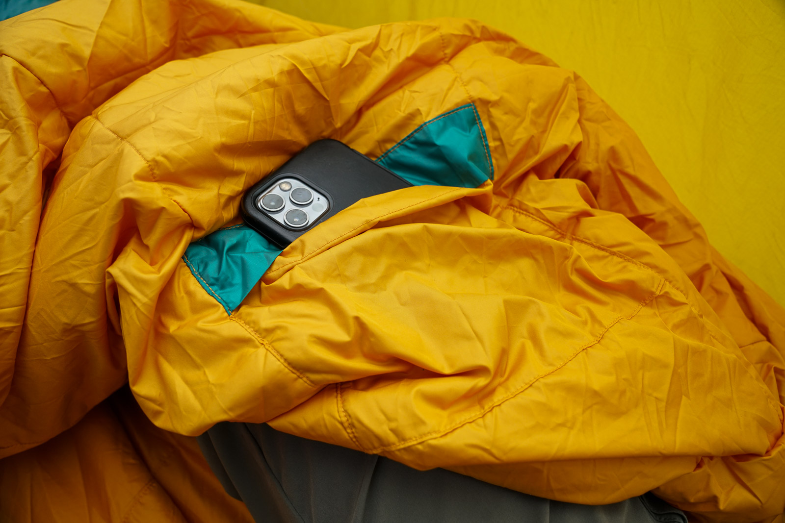 A close up of a smartphone sticking out of a sleeping bag stash pocket.