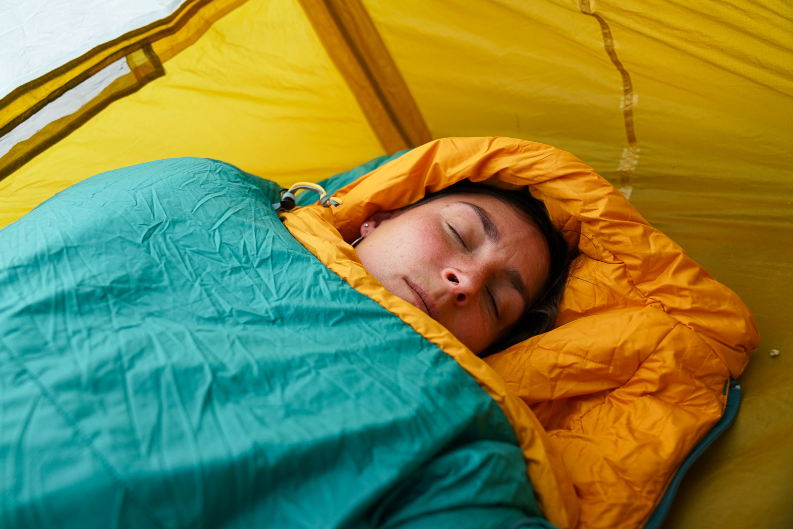 A close up of a sleeping person's face amidst a sleeping bag.