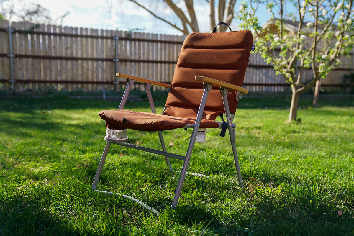 An empty folding camping chair sits on a lawn.