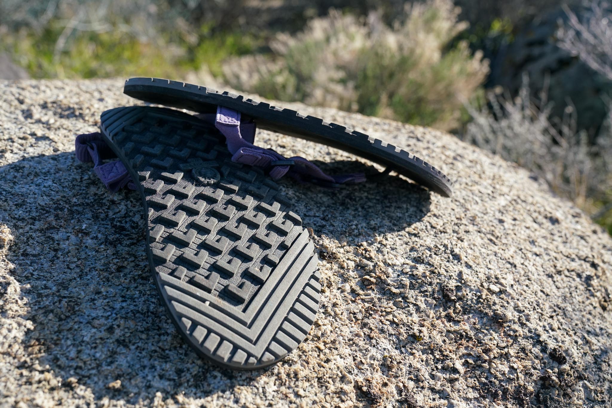 A close-up image of the underside of a pair of sandals sitting on a rock.