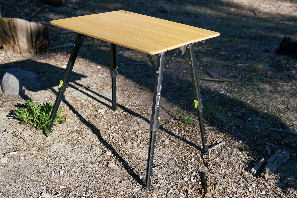 A close up of a camp table standing on the ground.