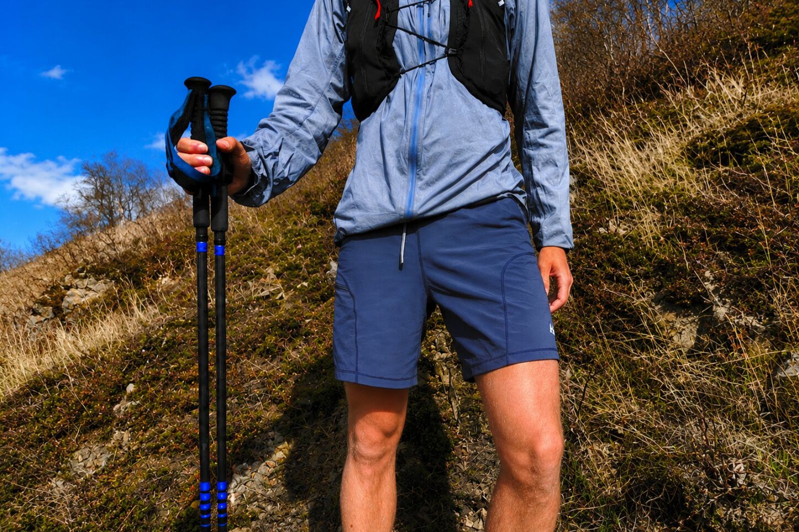 A closeup of blue shorts worn on a man standing on a trail.