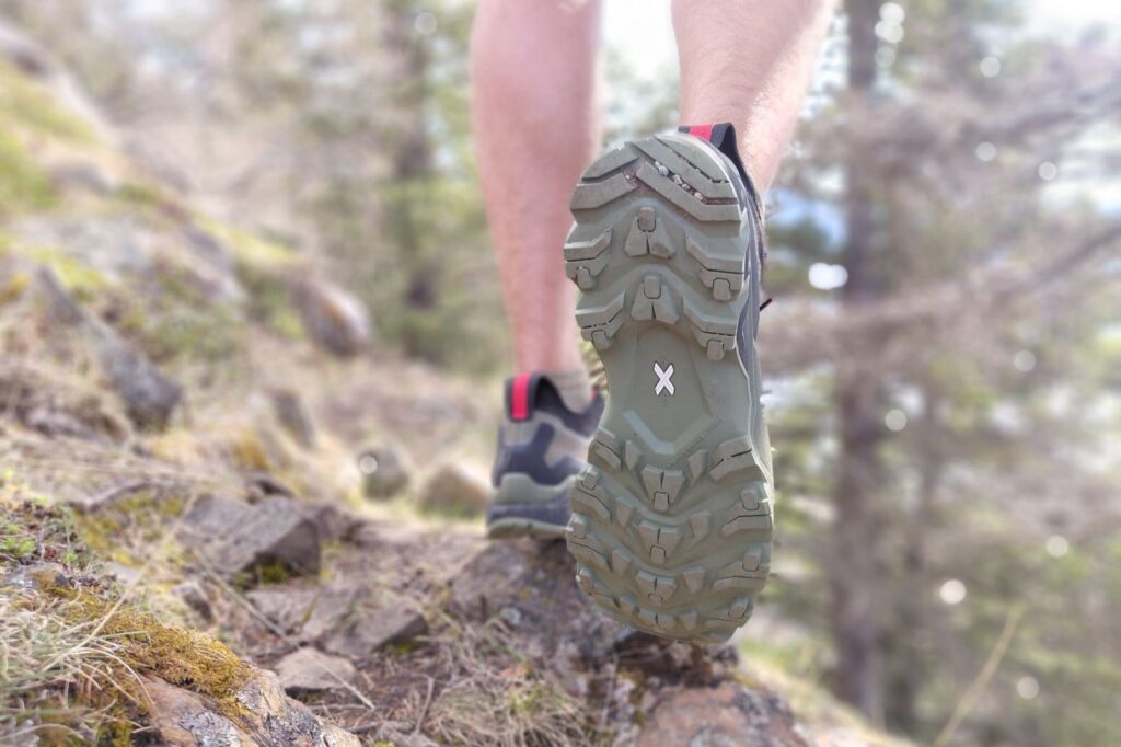 Close-up of a hiker's shoe sole on a rocky trail.