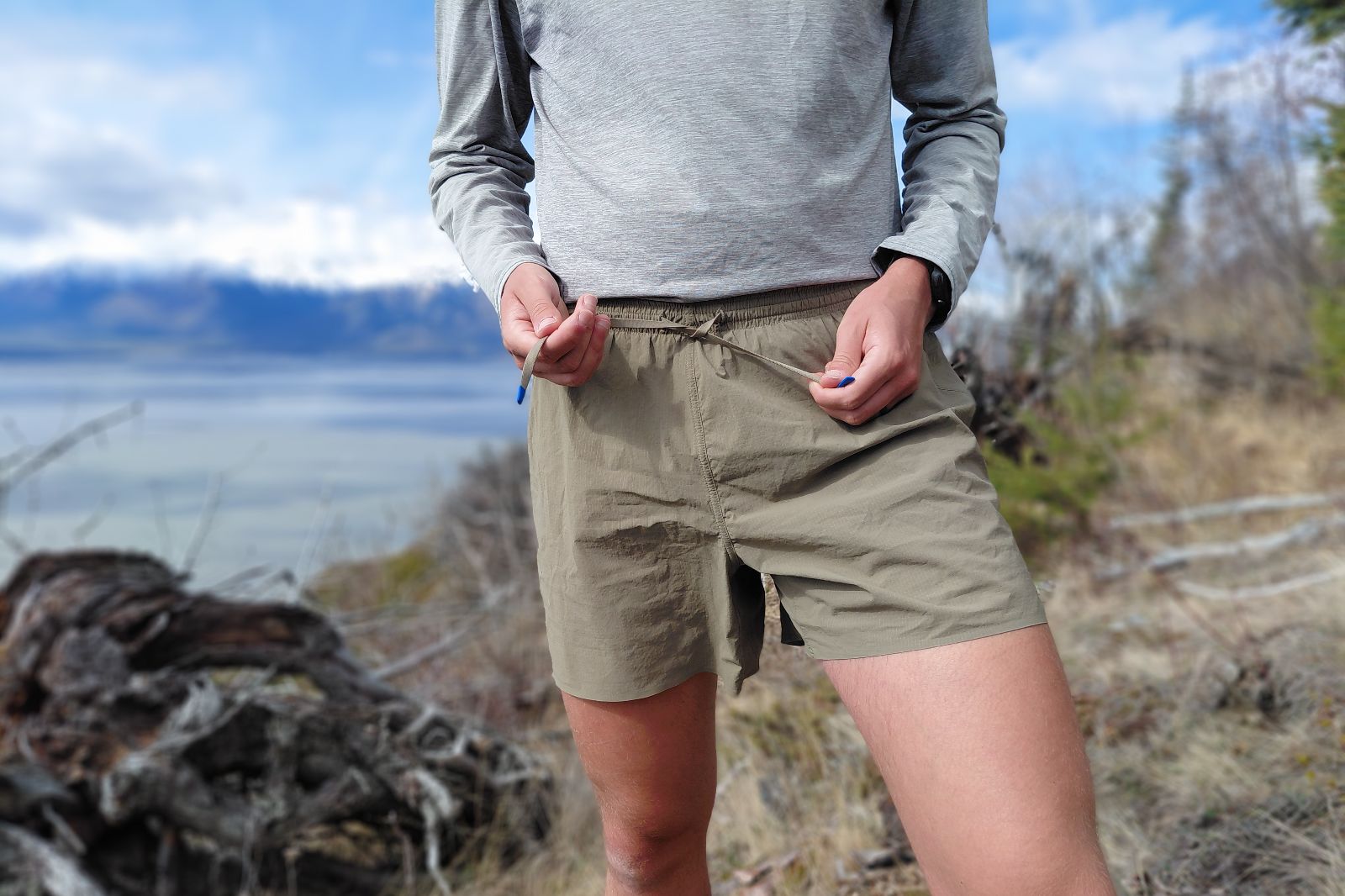 A man ties the string of his brown shorts.