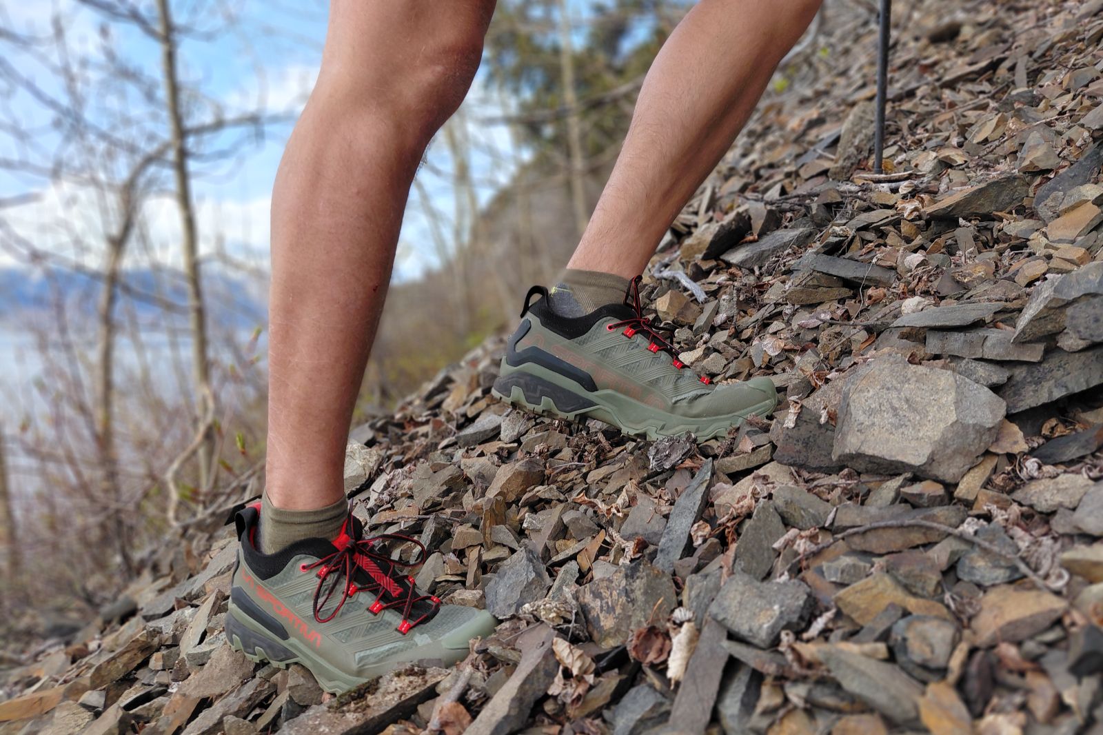 Hiker wearing green and red hiking shoes on a rocky slope.