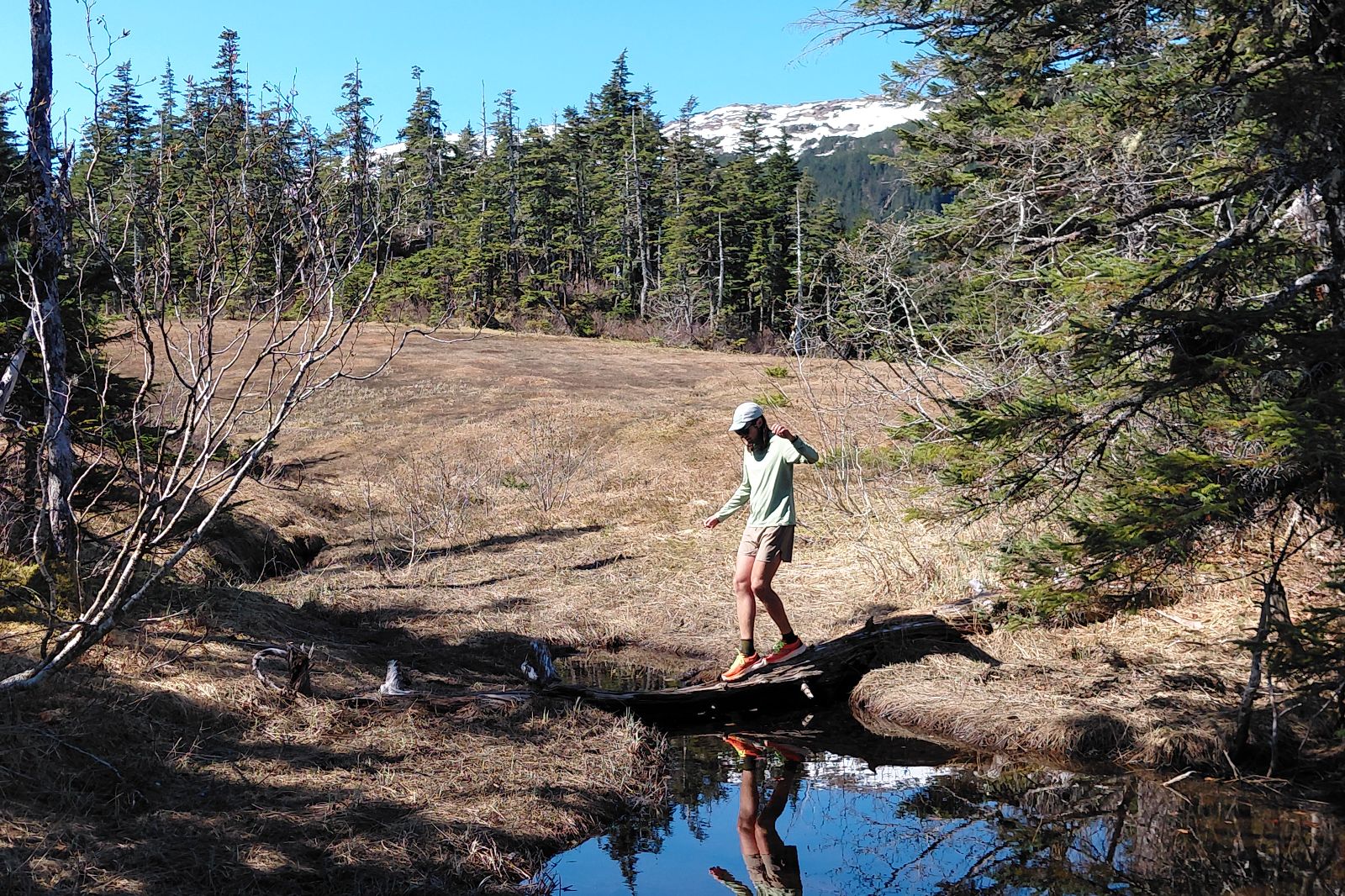 A man balances on a log over a small stream.