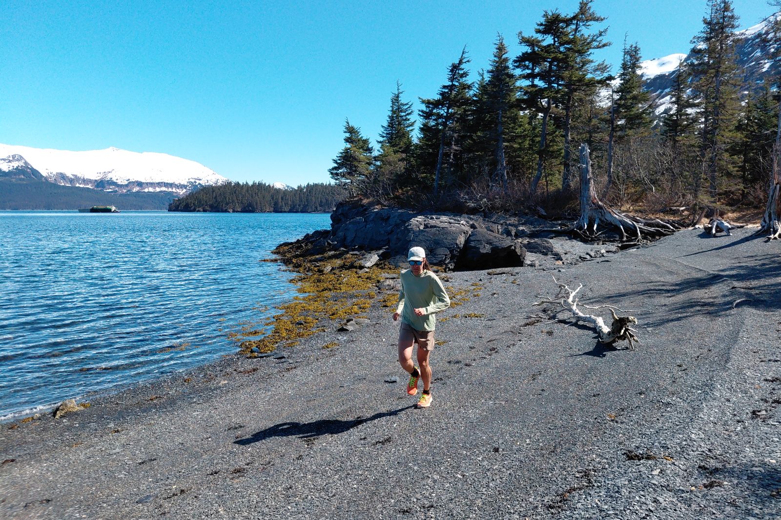 A runner jogs down a rocky beach.