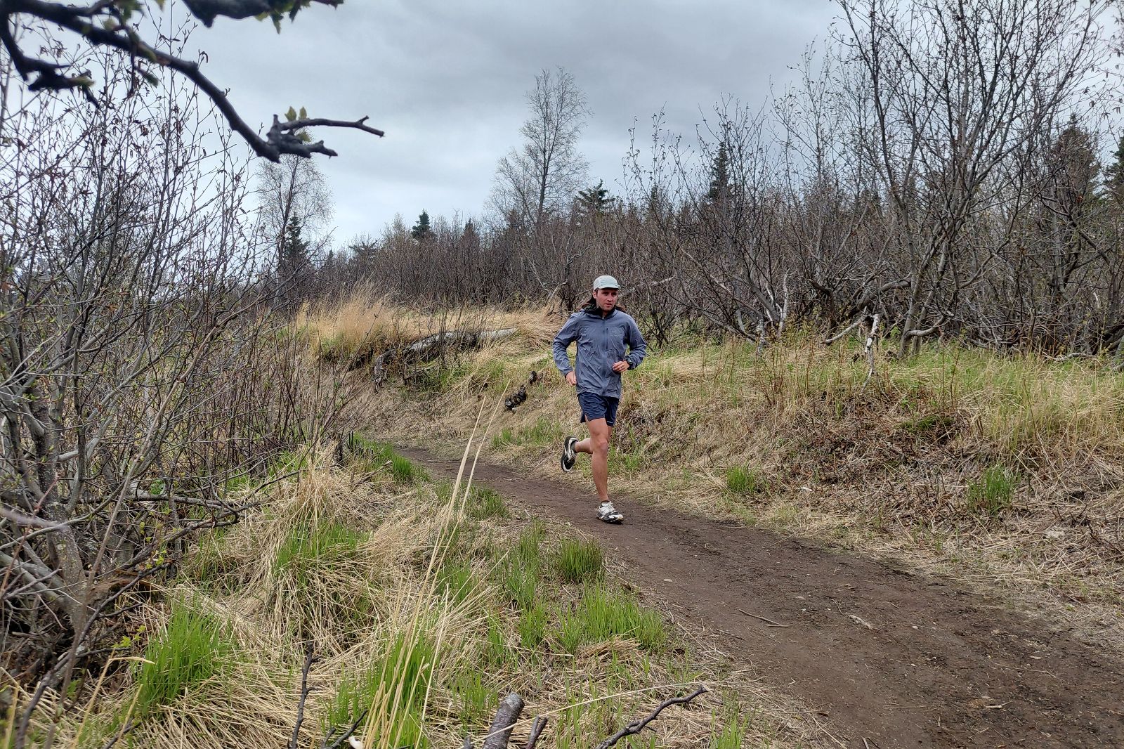 A man runs down a trail through tall grass.