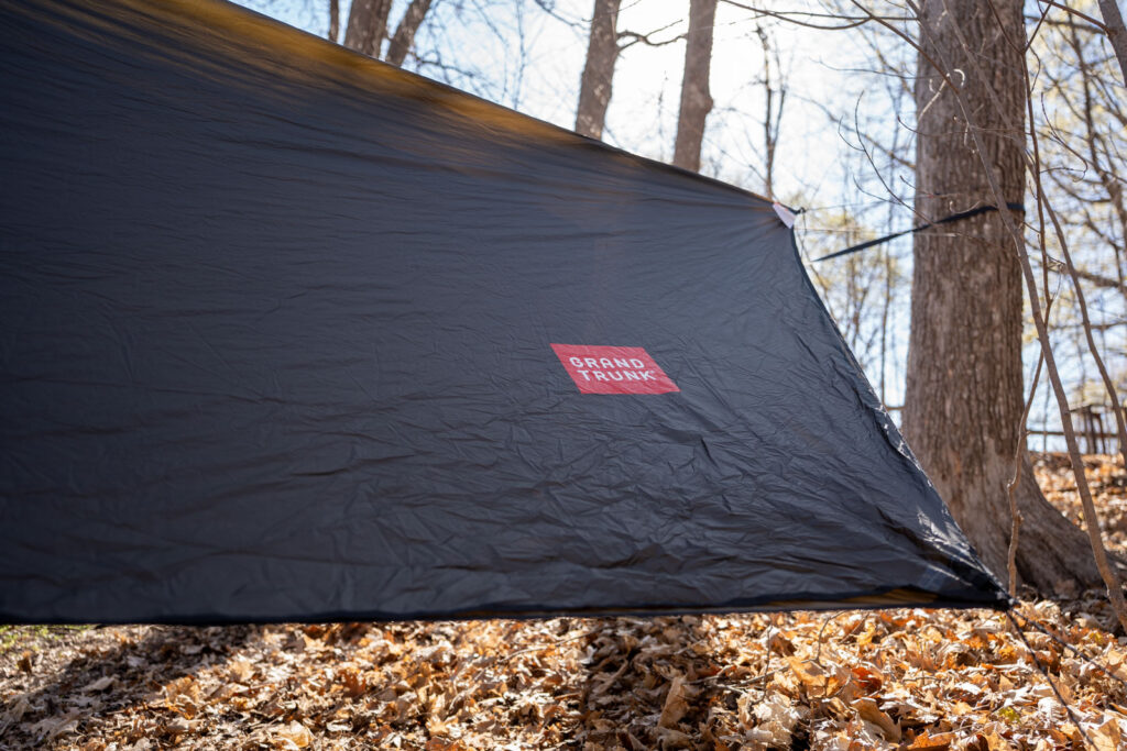 A hammock tarp pitched between two trees.