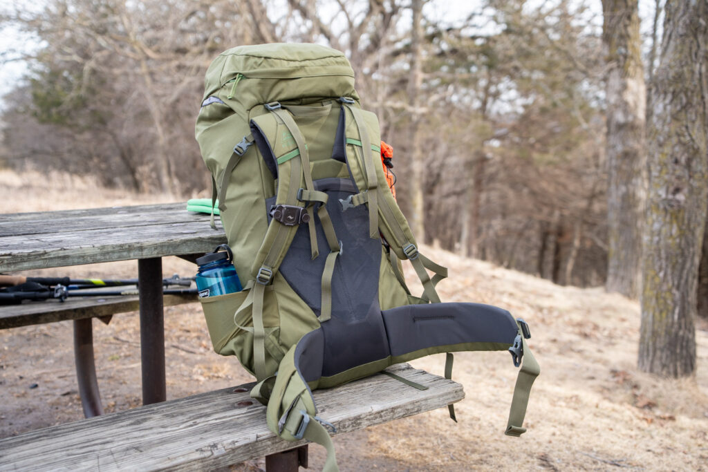A green backpack sits on a picnic table in a State Park