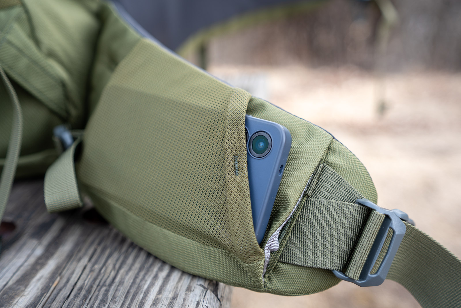 A mesh hip belt pocket on a backpack holds a blue phone