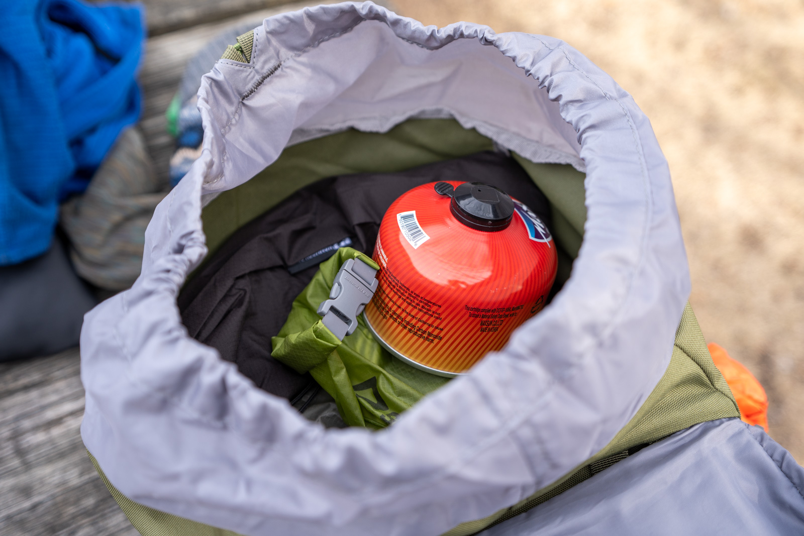 An opening to The top of a backpack with a fuel canister inside