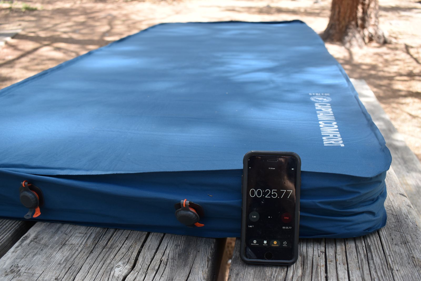 A cell phone time runs next to a self-inflating camping mattress that's slowly taking in air.