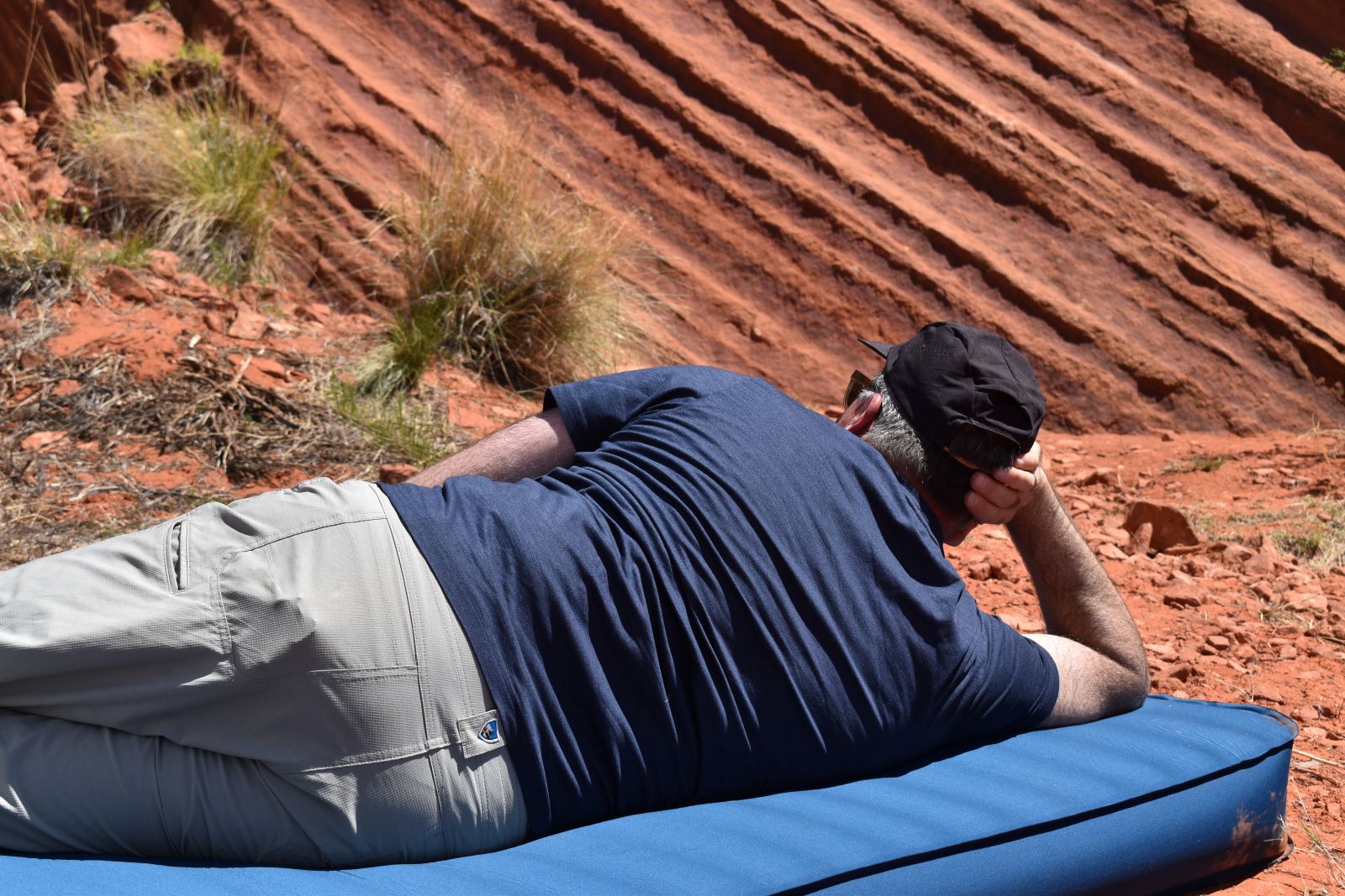 A male tester stares at striated red rock while laying on his side on the Big Agnes Captain Comfort