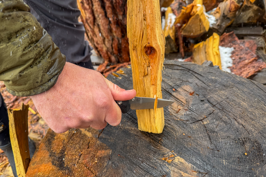 Mini Griptilian 556 hecho en banco que se utiliza para afeitar un rizo de un trozo de madera partida en el tocón de un árbol en condiciones húmedas.
