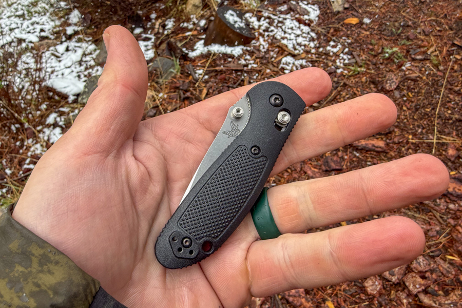Mini Griptilian 556 de banco cerrado y apoyado en una palma abierta al aire libre.