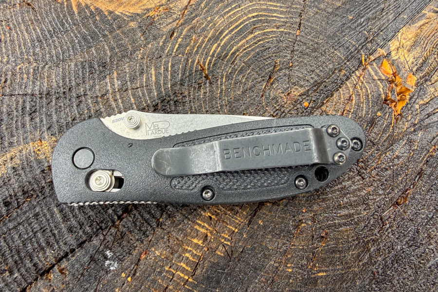 Mini Griptilian 556 hecho en banco cerrado sobre un tocón de árbol que muestra el clip de bolsillo reversible y el panel de mango texturizado.