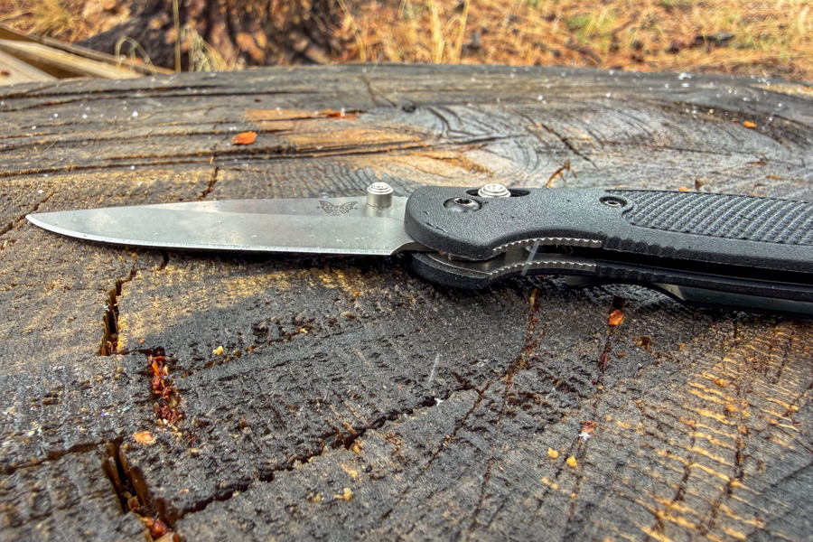 Mini Griptilian 556 hecho en banco, abierto en el tocón de un árbol desde un lado, mostrando la hoja con punta de caída y la forma del mango.