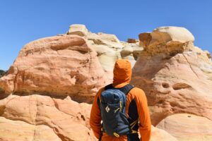 A male hiker stares at pink streaked hoodoos with the Black Diamond Pursuit on his back.