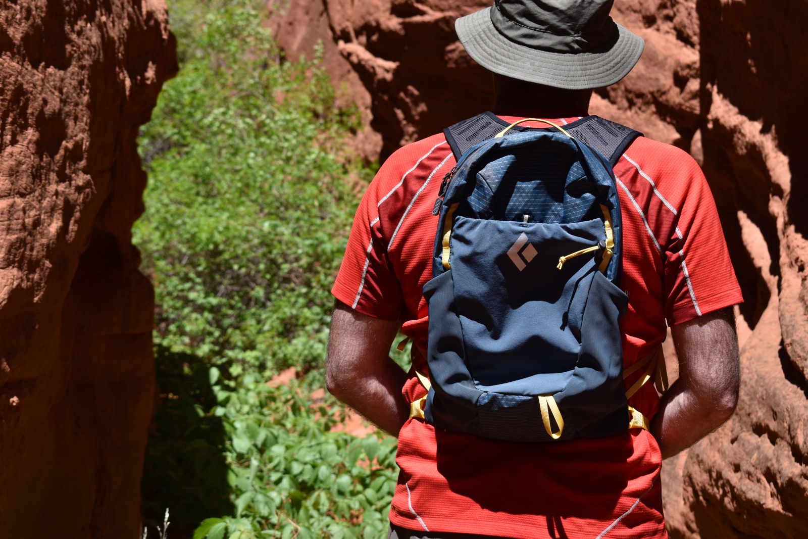 A hiker looks down a redrock slot canyon with the Black Diamond Pursuit 15 on his back