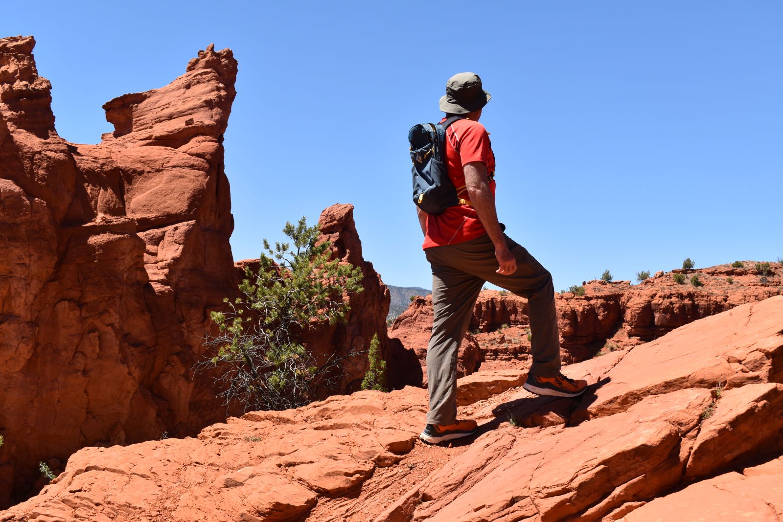 A male hiker wears the Black Diamond Pursuit 15 while hiking through a redrock canyon